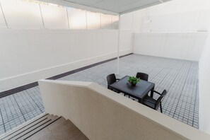 Una terraza en la azotea con una mesa, sillas, una planta en maceta y suelo de baldosas.