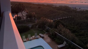 Een uitzicht op een strand bij zonsondergang, met een zwembad en ligbedden.
