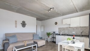 Un saló modern amb un sofà, taula de centre i una zona de menjador amb cadires.