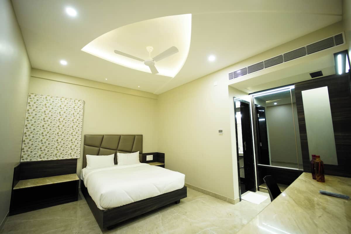 A modern bedroom with a bed, bedside tables, a ceiling fan, and a bathroom with a mirror and sink.