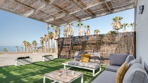A patio with a white sofa, a wooden coffee table, and a thatched roof. - Holiday Home 'La Casa del Caballo' with Sea Views, Private Pool and Wi-Fi (Adeje)