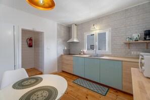 A modern kitchen with a white brick backsplash, a built-in stove, a window above the sink, and a wooden countertop.