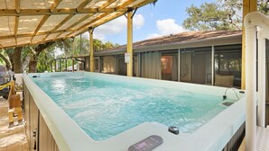 Ein Whirlpool im Freien mit Bedienfeld, umgeben von einer Holzterrasse und einem überdachten Bereich.