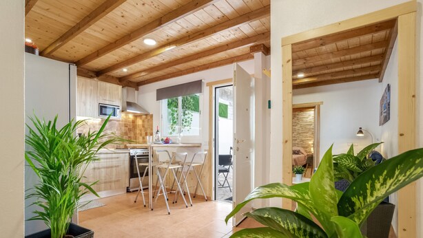 Een keuken met een eethoek, houten plafond en potplanten.