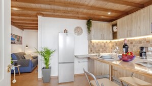 Een moderne keuken met houten kastjes, een witte koelkast, een spoelbak en een eethoek met stoelen.