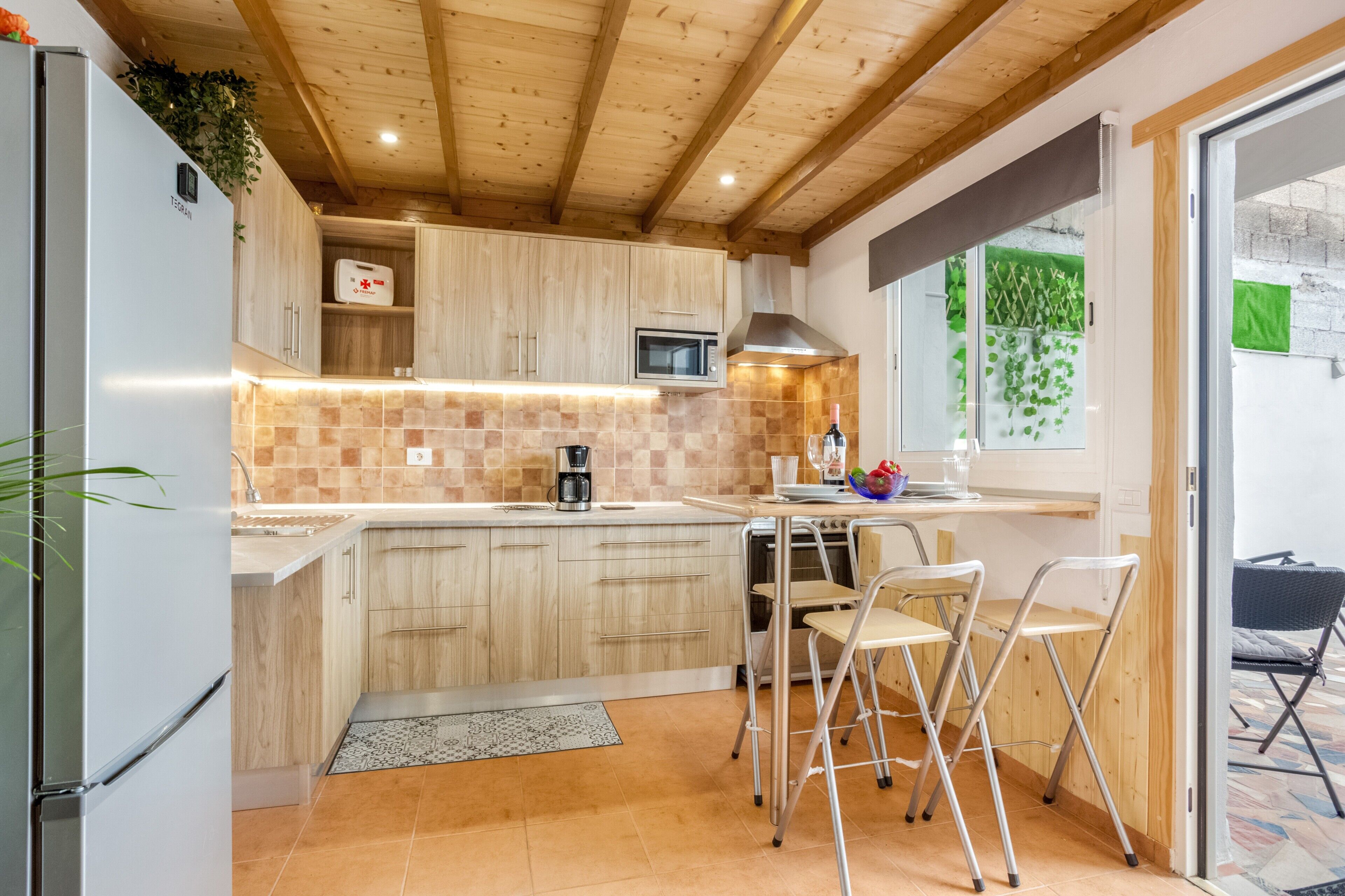 A kitchen with wooden cabinets, a microwave, a coffee maker, and a dining area with chairs.