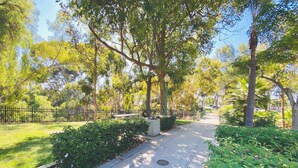 A park pathway lined with trees and bushes, a bench, and a trash bin. - Luxe Urban 2 Bedroom Steps from North Park (San Diego)