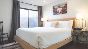 A hotel room with a large bed, a desk with a lamp, and a painting on the wall. - Luxe Urban 2 Bedroom Steps from North Park (San Diego)