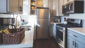A compact kitchen with stainless steel appliances, a microwave, a toaster, and a stove. - Luxe Urban 2 Bedroom Steps from North Park (San Diego)