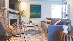A living room with a fireplace, a sofa, a chair, and a coffee table. - Luxe Urban 2 Bedroom Steps from North Park (San Diego)