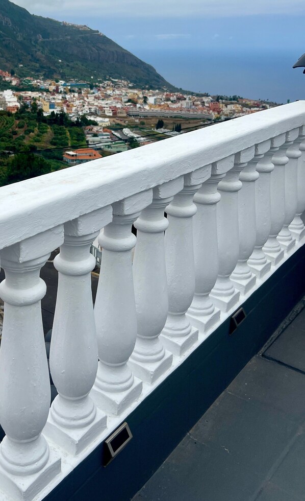 Una balaustrada blanca con vistas a un pueblo costero y una montaña al fondo.