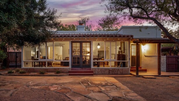 A modern house with a covered patio, large windows, and a stone patio.