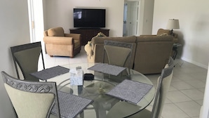 Una sala de estar con una mesa de vidrio, dos sofás y un televisor.