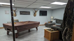 Une pièce comprenant une table de billard, un canapé et deux têtes de cerf fixées au mur.