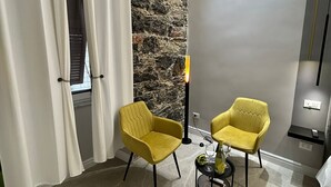 A modern room with two yellow chairs, a stone wall, and a large window with white curtains.