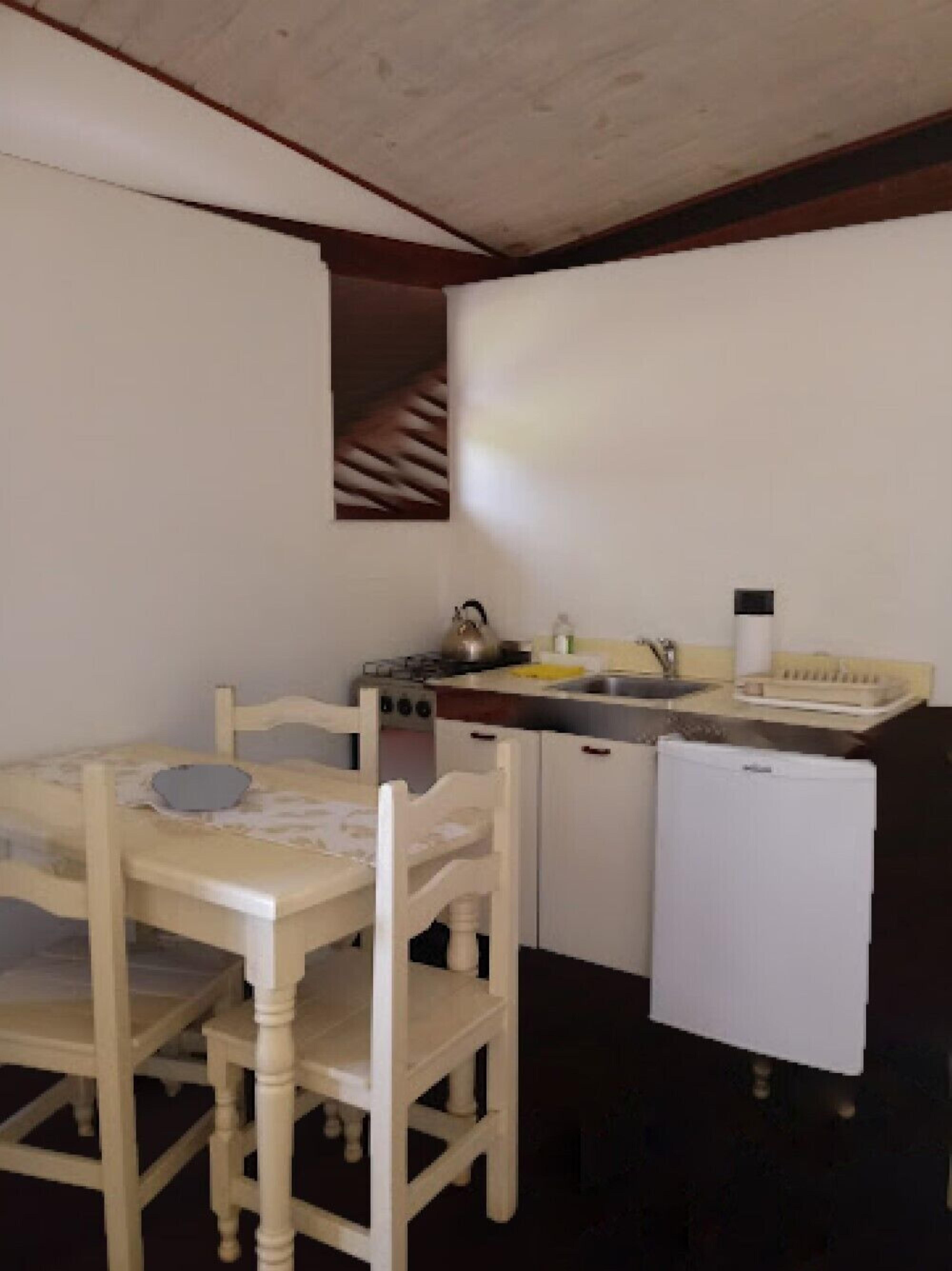 Une cuisine compacte comprenant une table et des chaises, un réfrigérateur, un évier et une cuisinière.