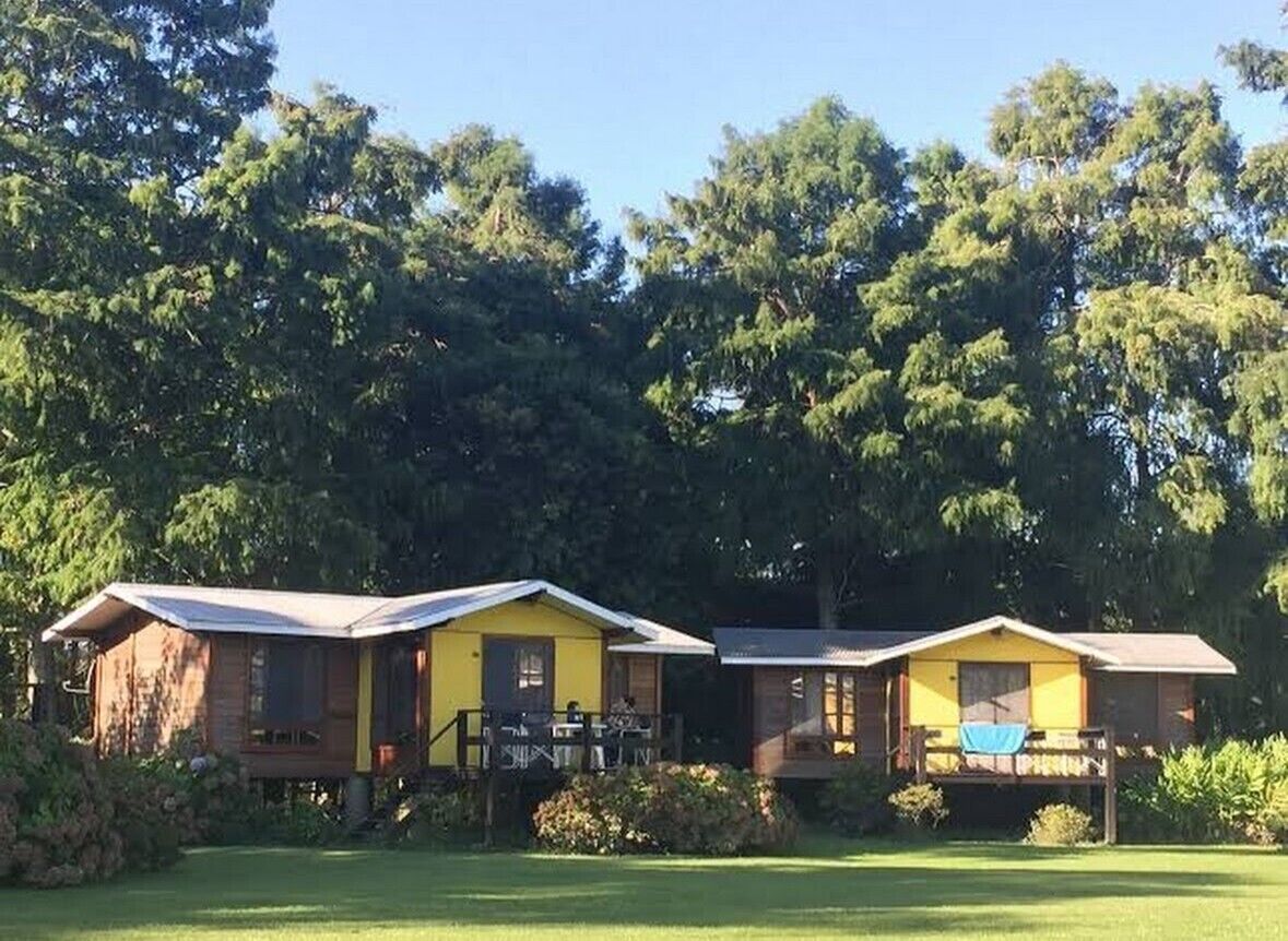 Two yellow cabins with wooden exteriors, each with a porch and a small deck area.