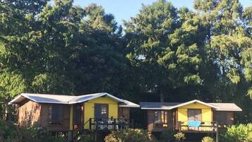 Two yellow cabins with wooden exteriors, each with a porch and a small deck area.