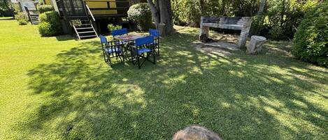 A well-maintained outdoor area with a dining table and chairs, a stone bench, and a building with a yellow facade.