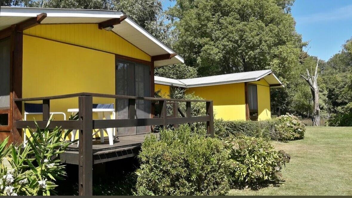 A yellow building with a deck and a covered seating area.