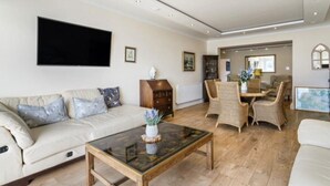 Un salon avec un canapé, une table basse et des fauteuils en osier.