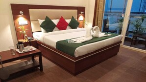 A hotel room with a large bed, bedside tables, a nightstand, and a view of the outside. - Hotel The Shivaay - Delight Inn  (Rishikesh)