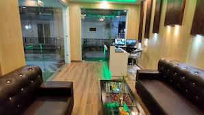 A lobby with leather sofas, a reception desk, and a glass partition. - Hotel The Shivaay - Delight Inn  (Rishikesh)