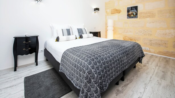 Ein Schlafzimmer mit einem Bett, Nachttischen, einem Teppich und einer Steinwand.