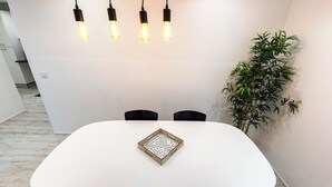 Ein moderner Essbereich mit einem weißen Tisch, vier Stühlen und hängenden Lampen.