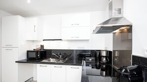 Eine moderne Küche mit weißen Schränken, einer schwarzen Arbeitsplatte, einer Kaffeemaschine und einem Toaster.