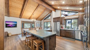A spacious kitchen with a large island, wooden ceiling beams, and modern stainless steel appliances. - Edgewater Escape in Dollar Point Tahoe City (Tahoe City)