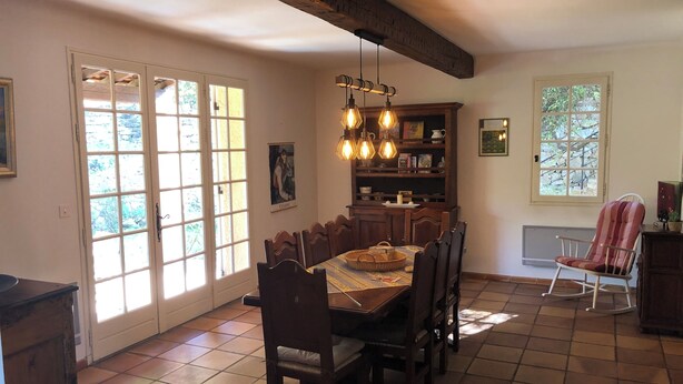 A dining area with a wooden table, chairs, and a hanging light fixture.