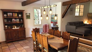 A dining area with a wooden table and chairs, a bookshelf, and a cozy seating area with a sofa and a fireplace.