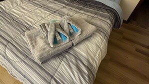 Un lit avec une couverture à rayures et deux serviettes pliées.