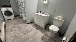 Une petite salle de bain équipée d’un lave-linge, d’un lavabo et de toilettes.