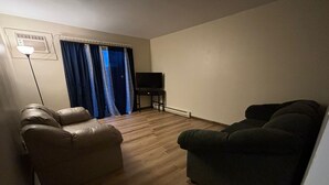 Un salon avec deux canapés en cuir, un téléviseur à écran plat posé sur un meuble et une lampe sur pied.
