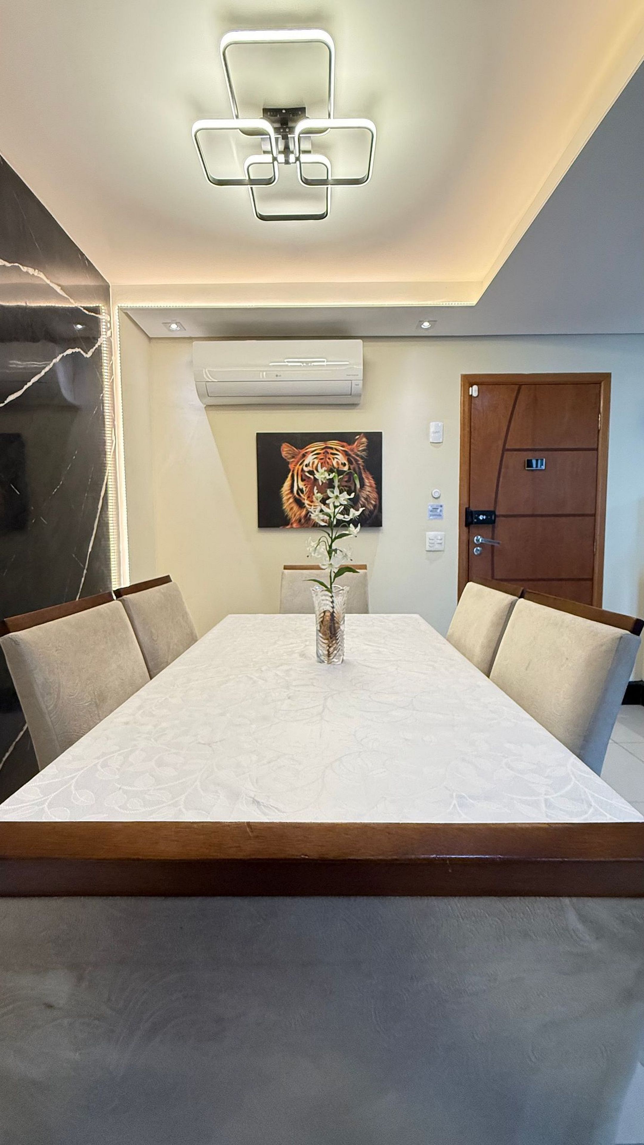A conference room with a marble table, chairs, a vase with flowers, an air conditioning unit, and a tiger painting on the wall.
