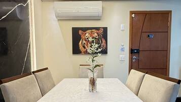 A conference room with a marble table, chairs, a vase with flowers, an air conditioning unit, and a tiger painting on the wall.