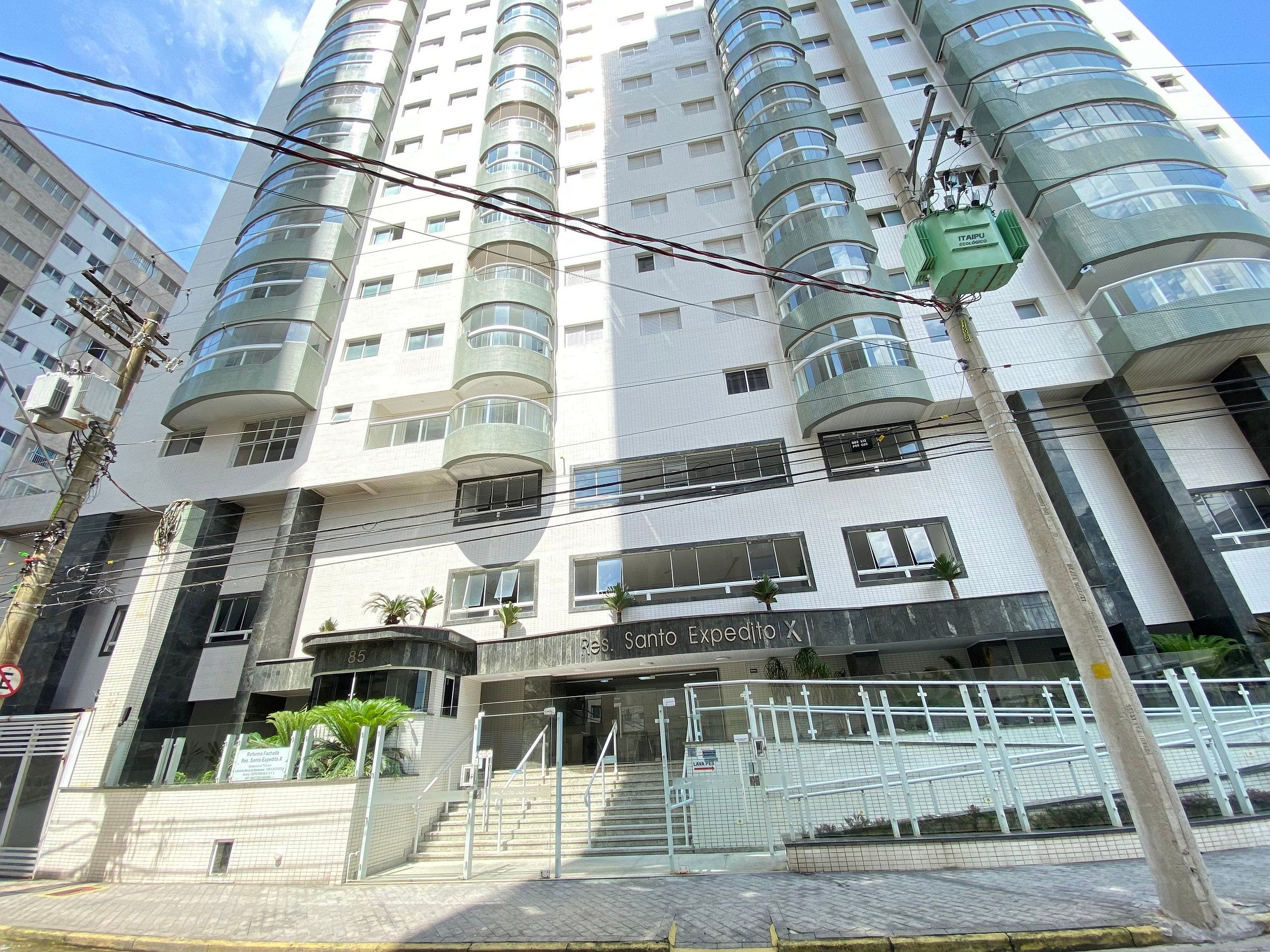A multi-story building with a modern design, featuring a central entrance with a staircase and a sign that reads "Res. Sanio Expedito X".