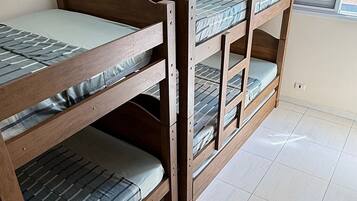 Una habitación con literas, ventilador de techo y ventana con persianas.