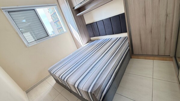 Un dormitorio pequeño con cama, ventana y armario.