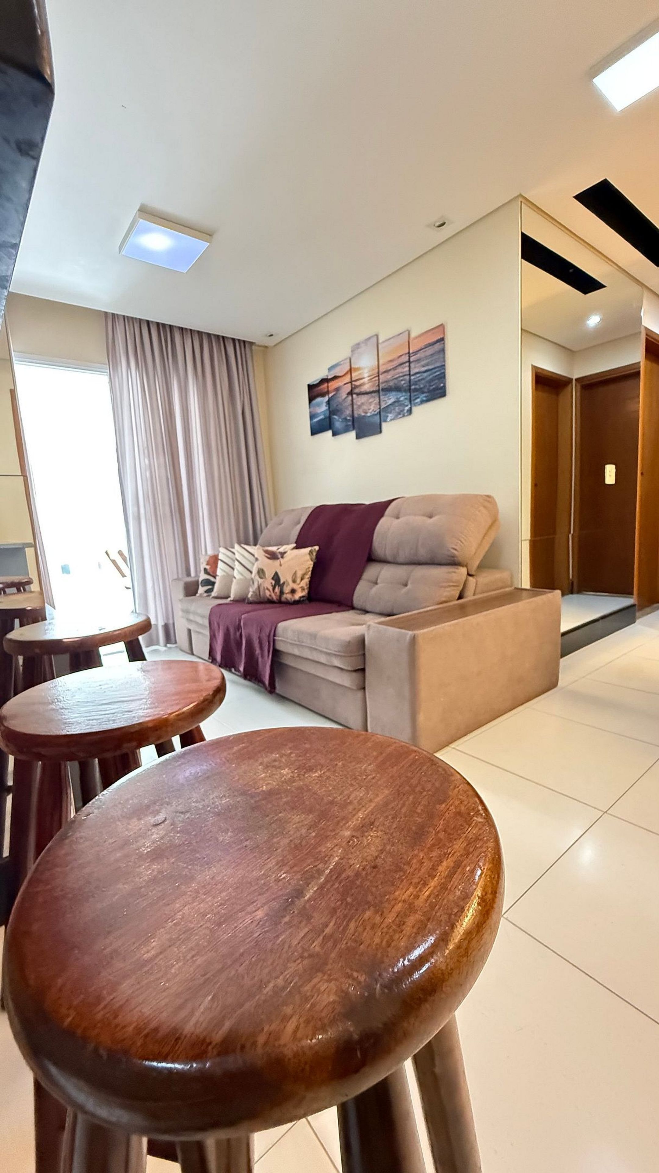 A living room with a sofa, a coffee table, and a dining area with stools.