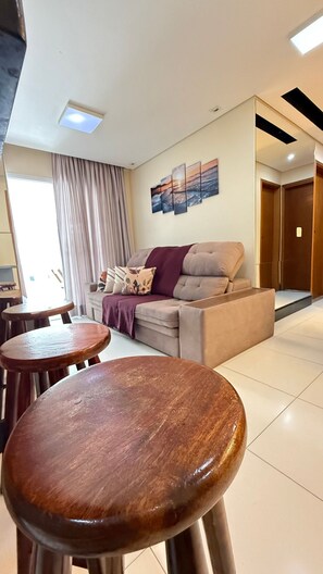 Una sala de estar con sofá, una mesa de centro y un comedor con taburetes.