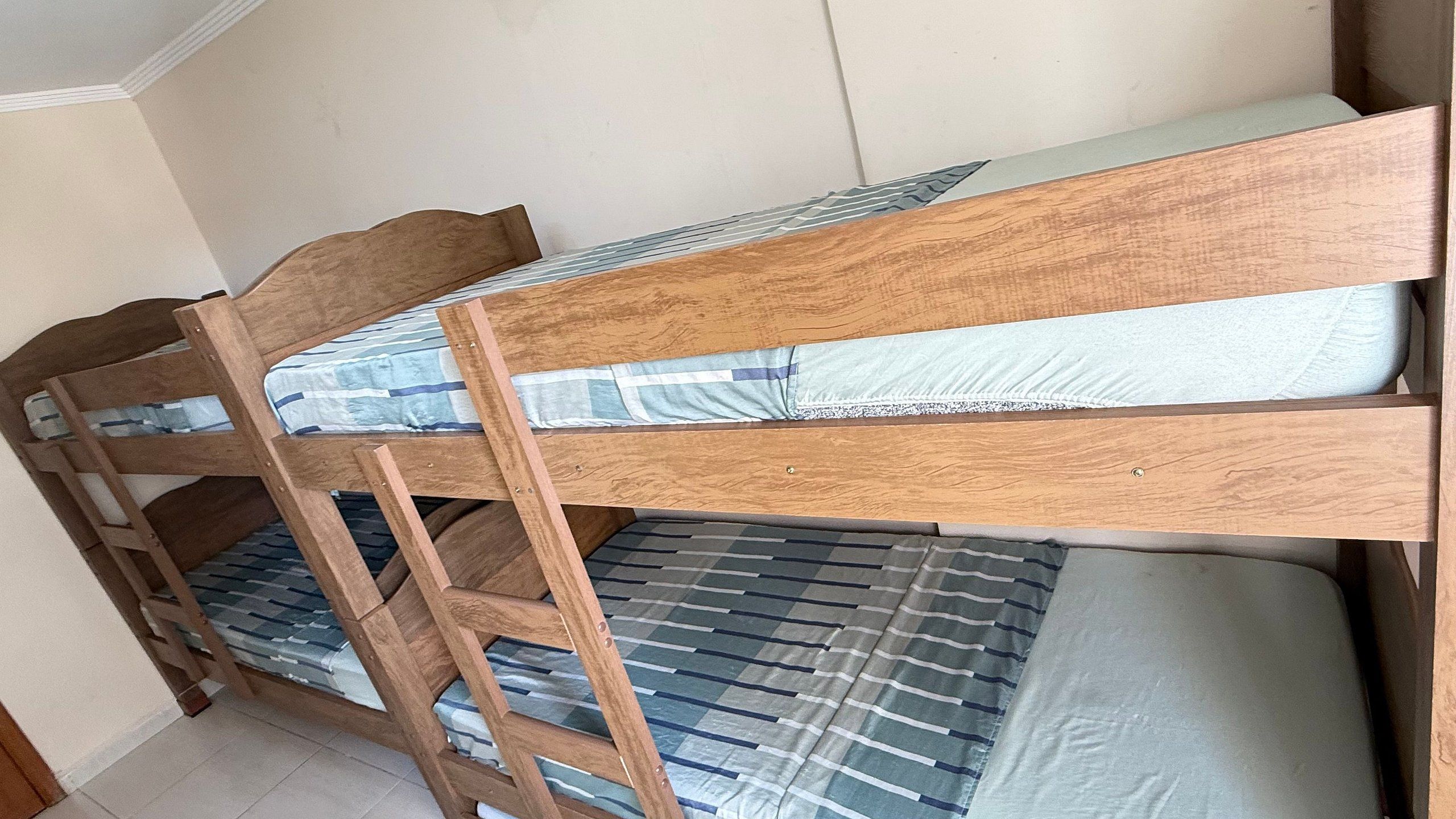 Uma cama beliche com escada, cabeceira de madeira e roupa de cama listrada.