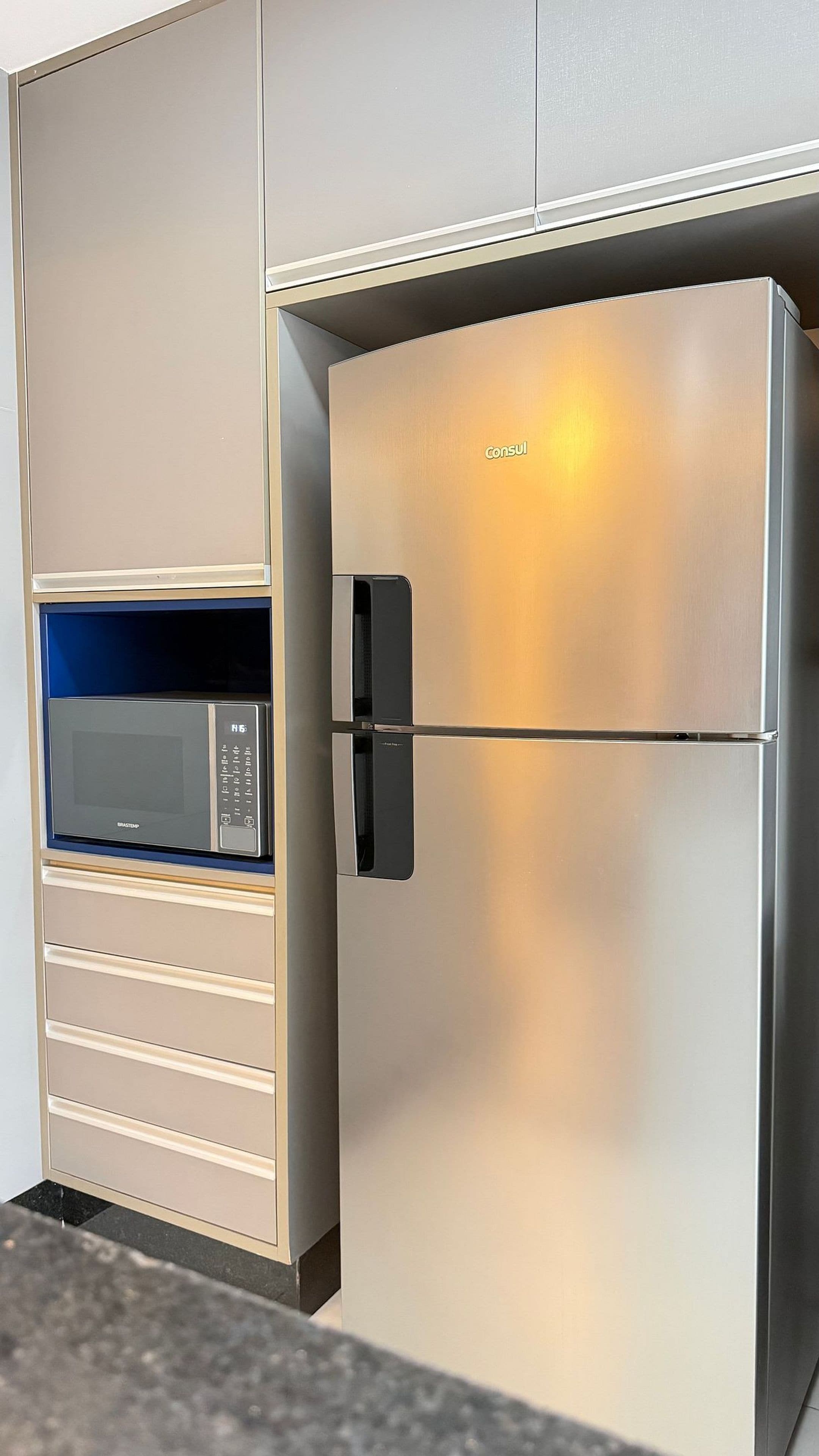Un refrigerador de acero inoxidable con pantalla digital y microondas integrado en los armarios.