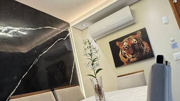 A modern hotel room with a dining area, a painting of a tiger, and a vase with flowers.