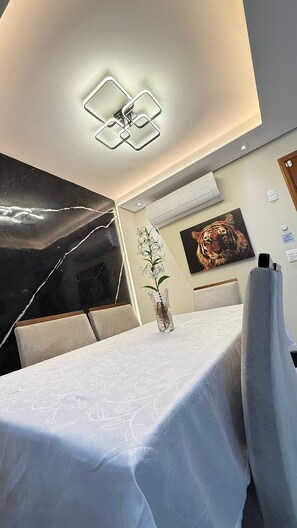 Una habitación de hotel moderna con un comedor, un cuadro de un tigre y un jarrón con flores.