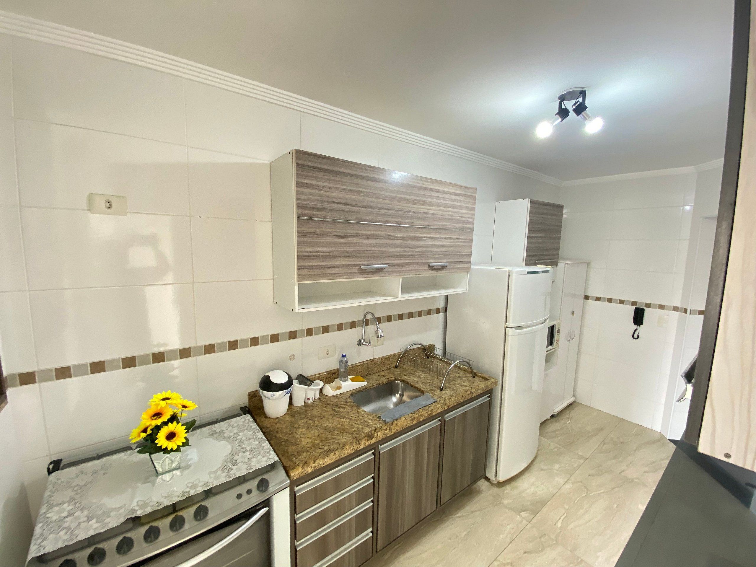 A modern kitchen with a granite countertop, stainless steel appliances, and a wooden backsplash.