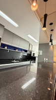 Una cocina moderna con un lavamanos de acero inoxidable, una estufa e iluminación colgante.