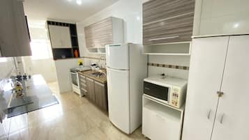 A modern kitchen with white cabinets, a built-in microwave, and a stainless steel oven.